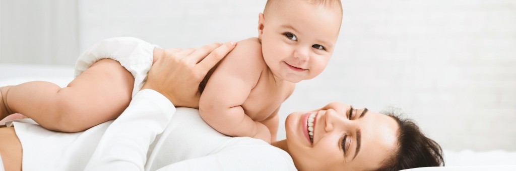 Smiling mother with baby on chest.