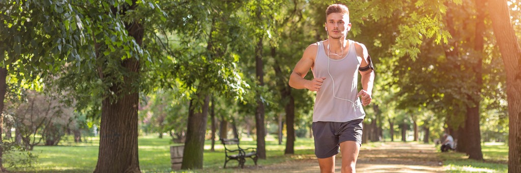 Man jogging in sunny park.