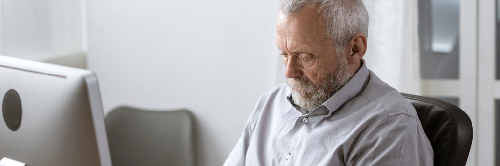 Elderly man concentrating at desk.