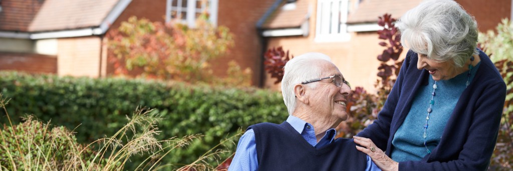 Elderly couple smiling outdoors.