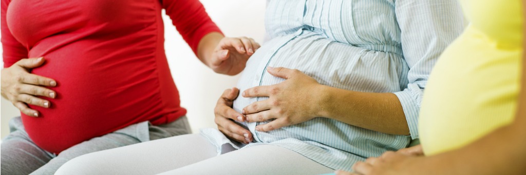 A pregnant woman offering a supportive gesture to another pregnant woman