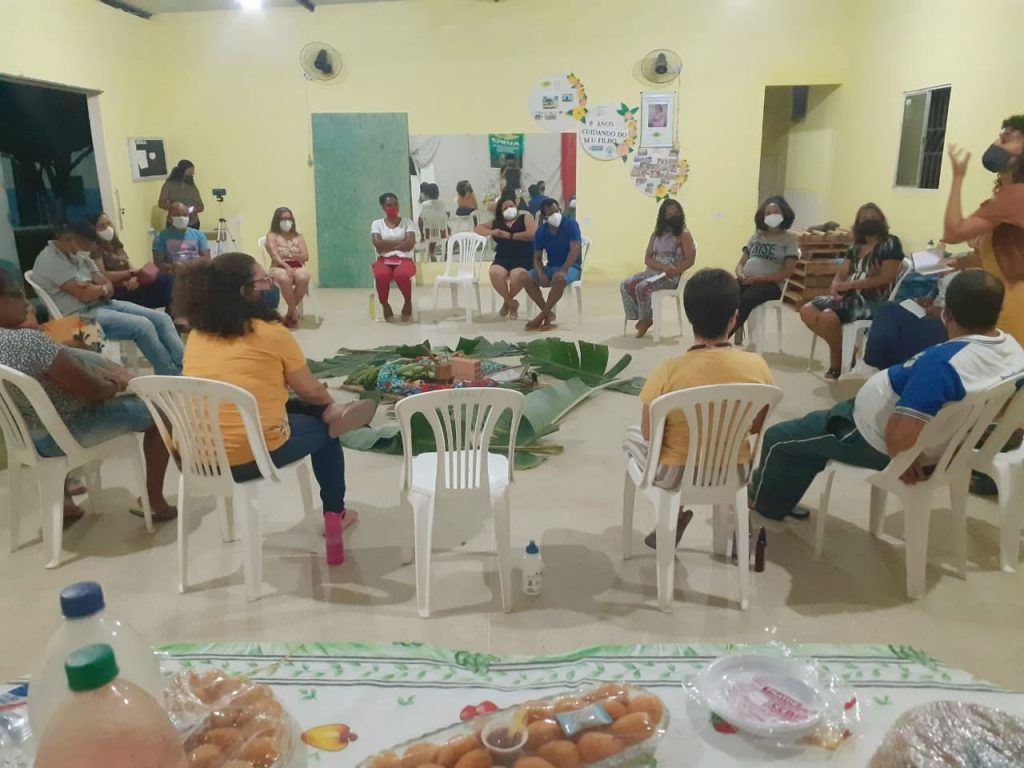 A group of people sat in a cricle in a large room