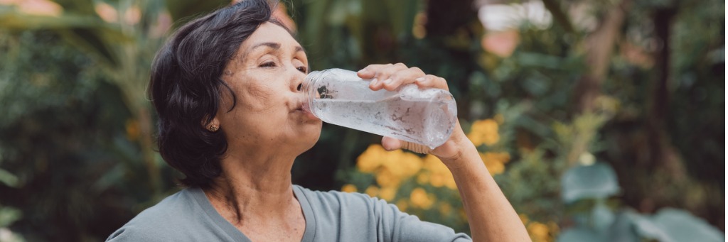 Woman drinking water outdoors.