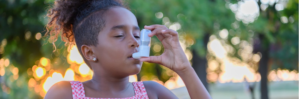 Child using an inhaler outdoors.