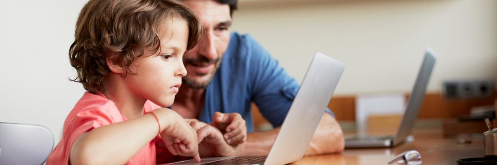 Child using laptop with adult.