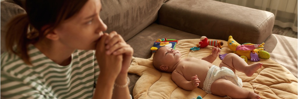 Woman watching sleeping baby on sofa.