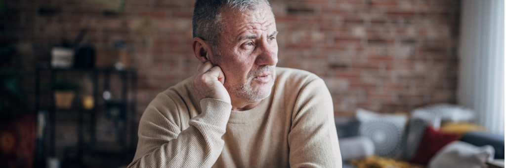 Elderly man gazing thoughtfully outside.