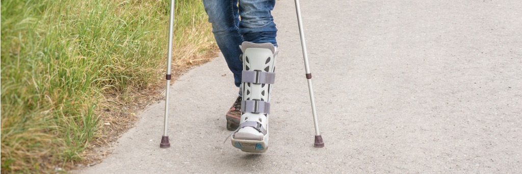 Person walking with crutches outside.