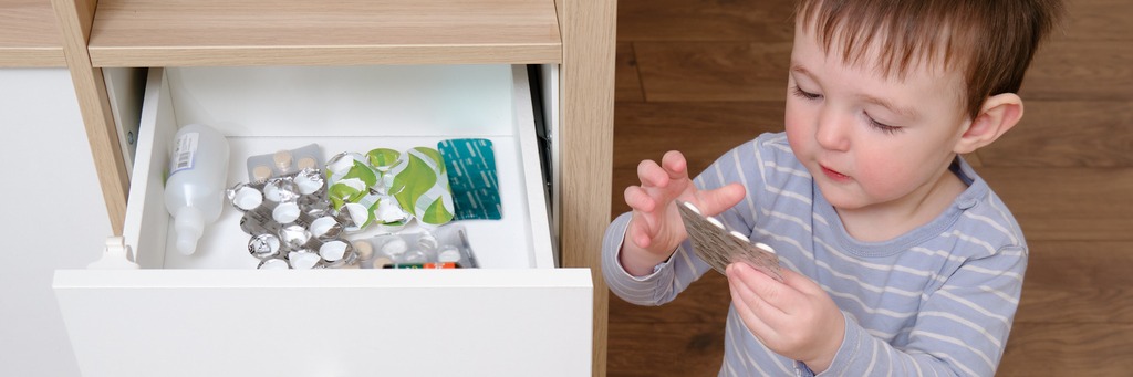 Child examining blister pack near drawer.