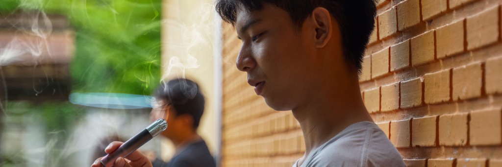 Person vaping near brick wall.